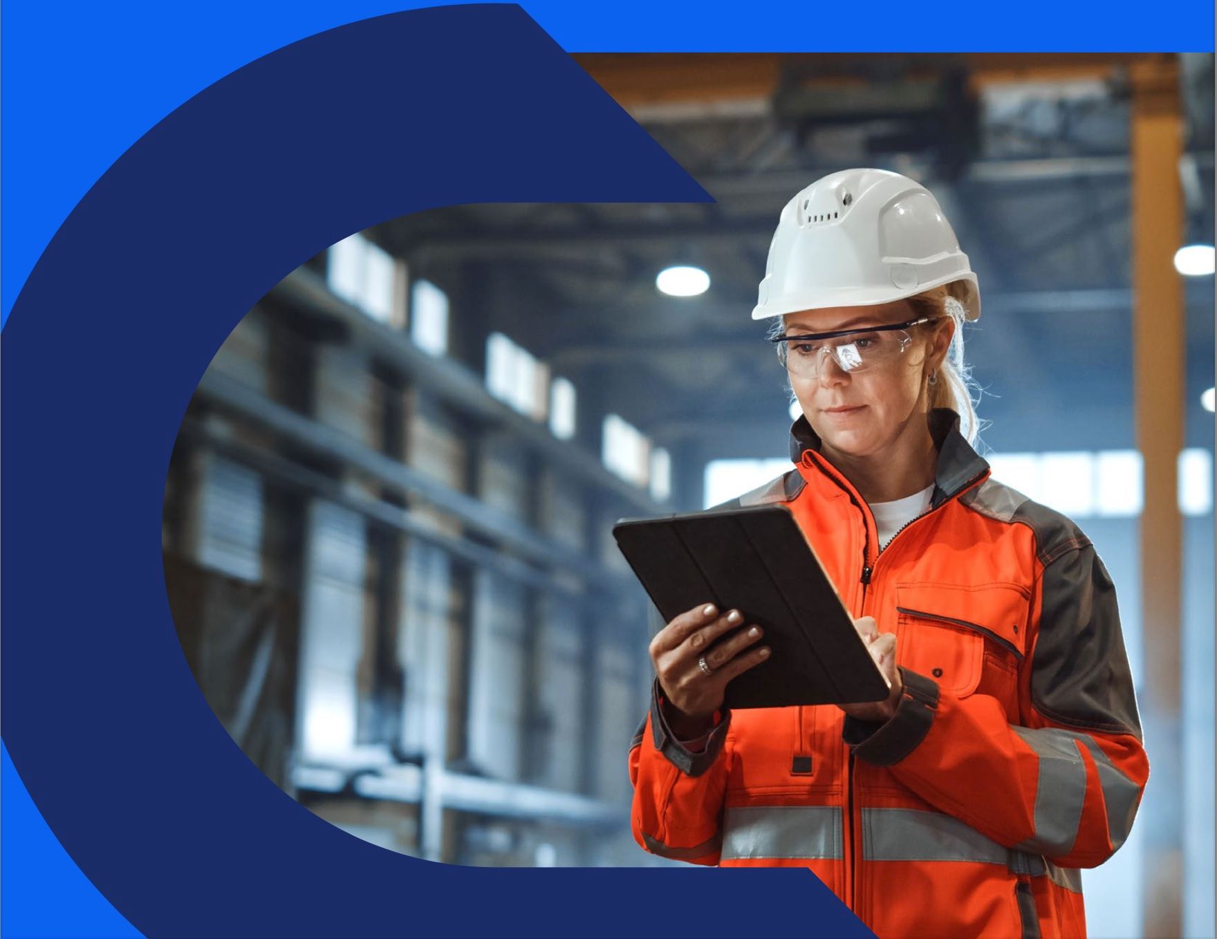 An engineer in a hard hat reviewing data on a tablet in a factory